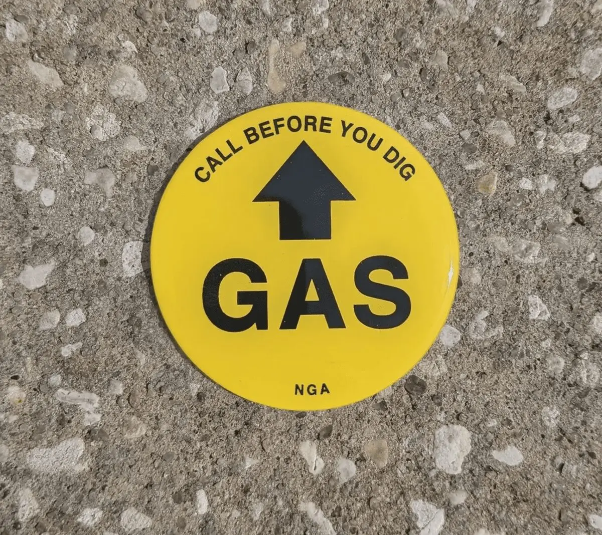 Yellow gas warning sign on concrete surface.