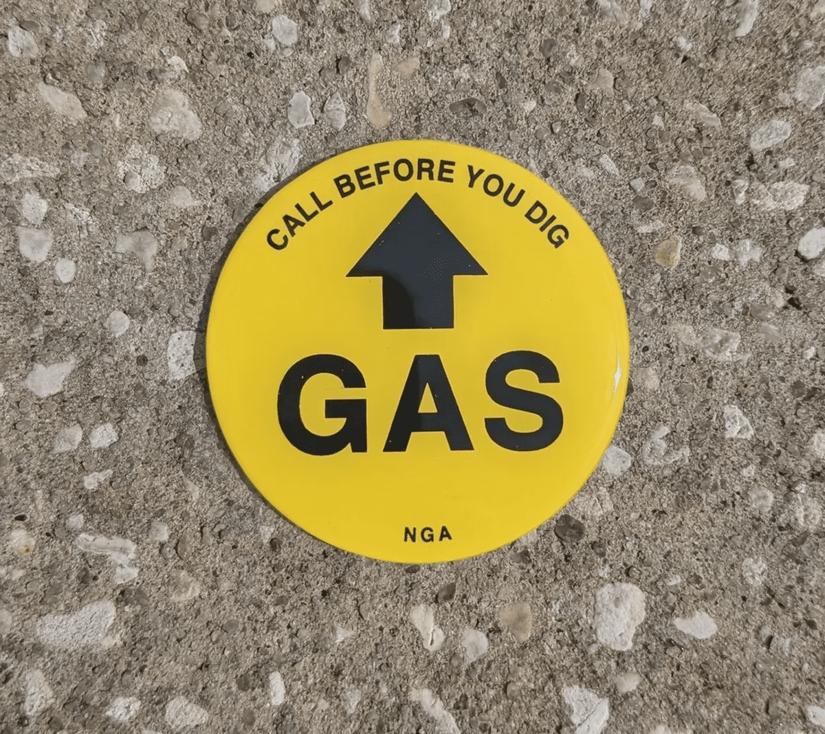 Yellow gas warning sign on concrete surface.