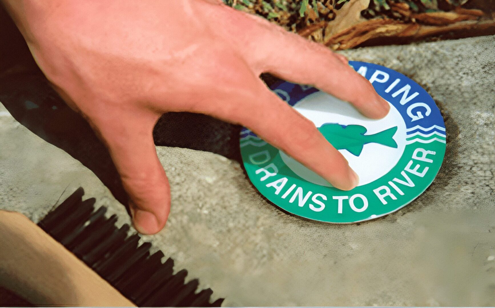 Hand placing "No Dumping" sign on ground.