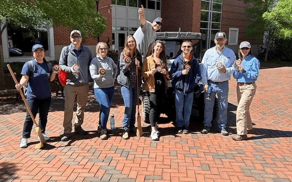 Group of people holding small awards outdoors.