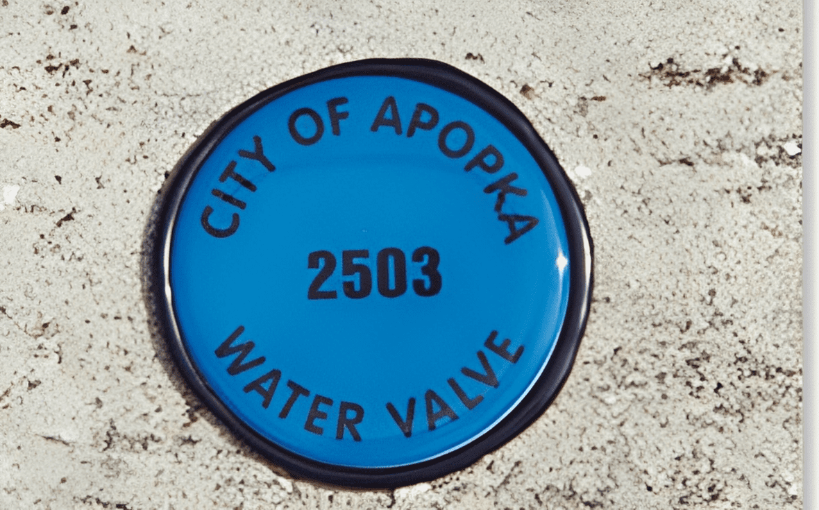 Blue Apopka water valve cover on concrete.